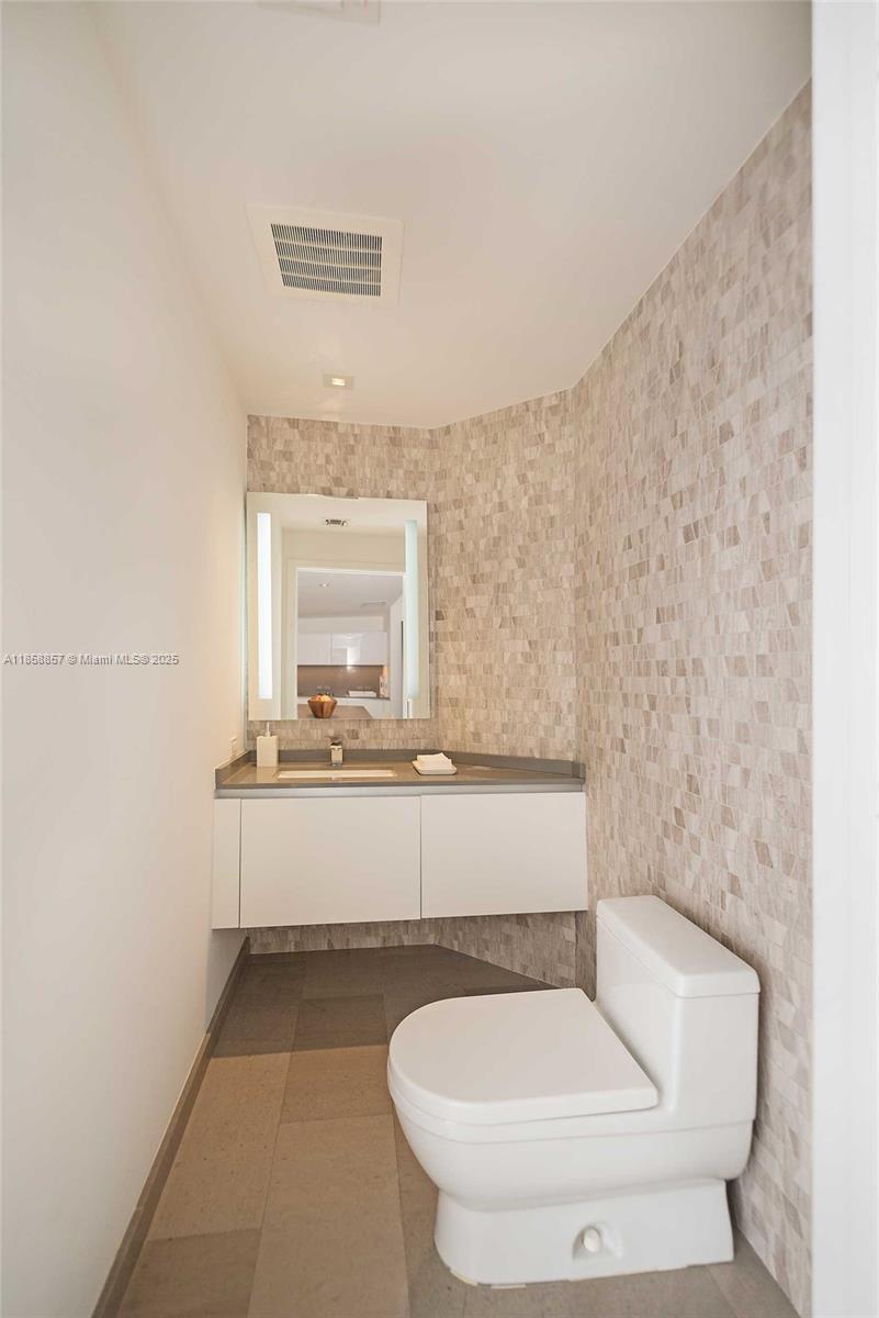68 Southeast 6th Street, Unit 1008 Miami, FL 33131 - Photo 36 of 37 a bathroom with a toilet a sink and mirror