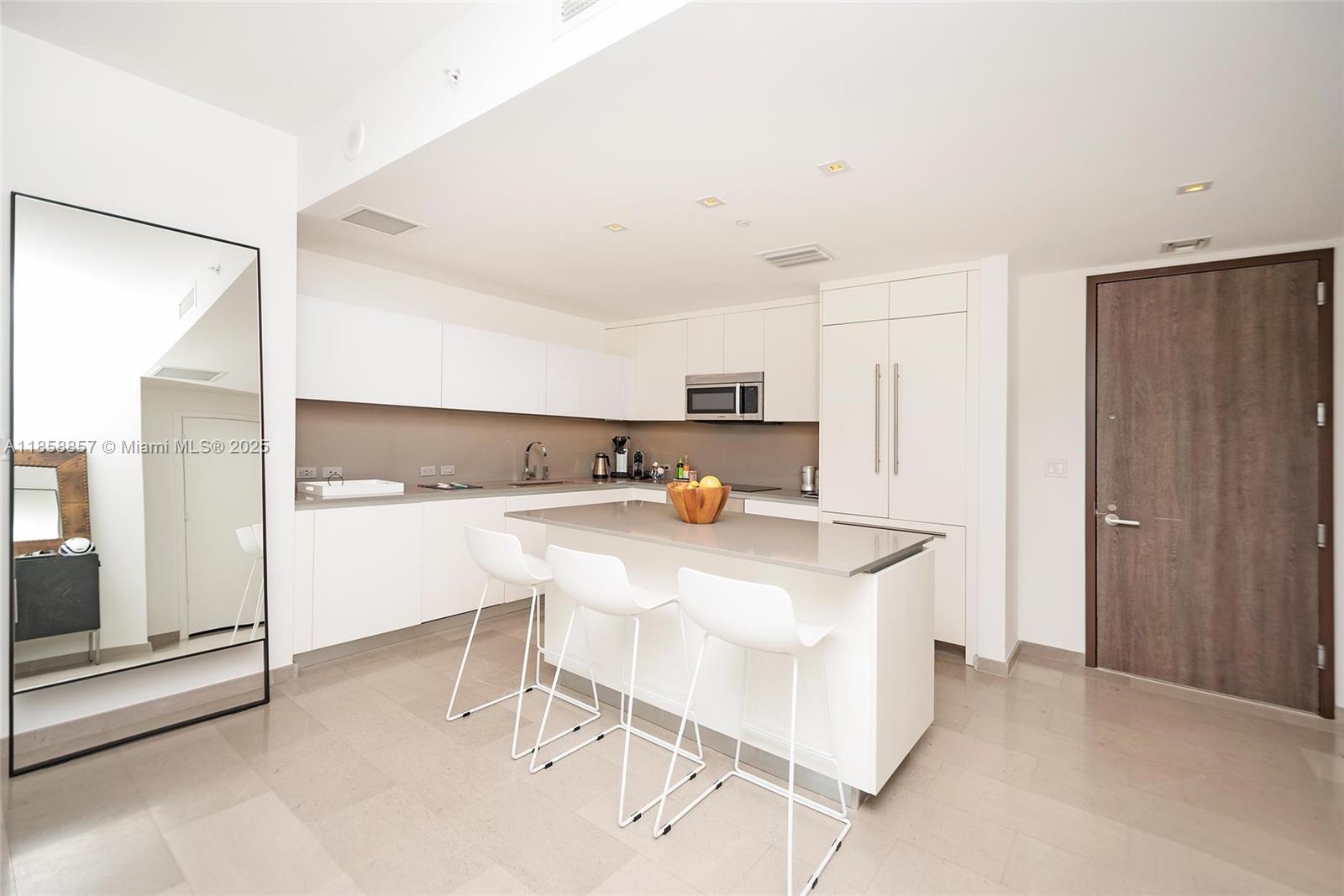 68 Southeast 6th Street, Unit 1008 Miami, FL 33131 - Photo 5 of 37 a kitchen with kitchen island a stove a sink and a refrigerator with white cabinets