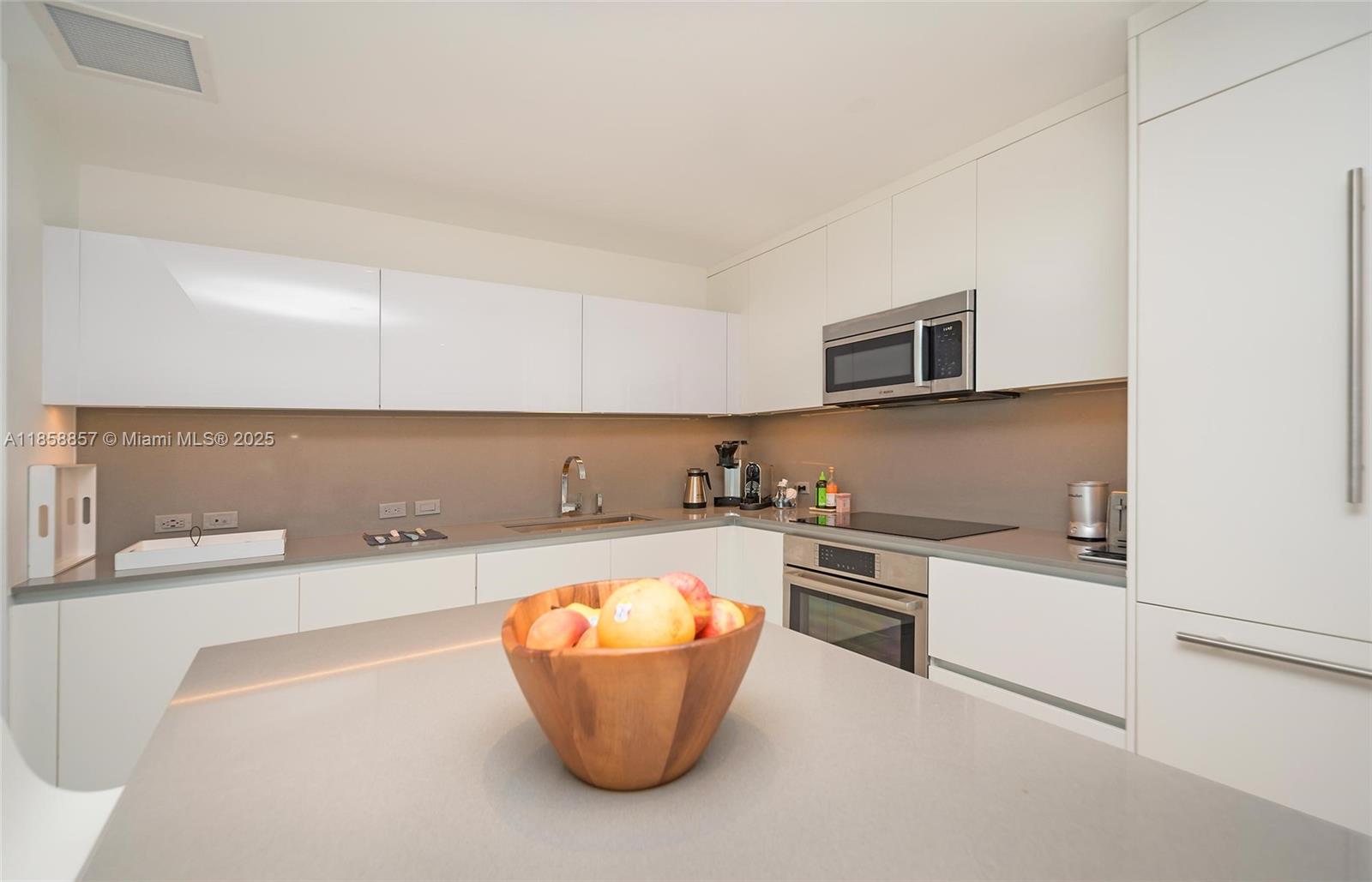 68 Southeast 6th Street, Unit 1008 Miami, FL 33131 - Photo 6 of 37 a kitchen with a sink a stove top oven and kitchen island