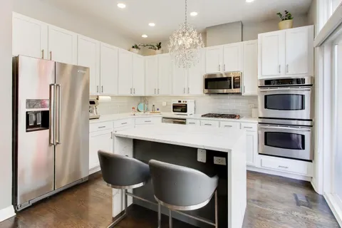 a kitchen with stainless steel appliances a stove a refrigerator and a microwave