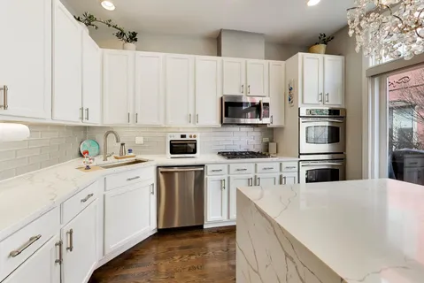 a kitchen with stainless steel appliances granite countertop a refrigerator sink and white cabinets