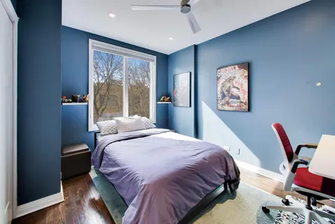 a bedroom with a bed painting on wall and a large window