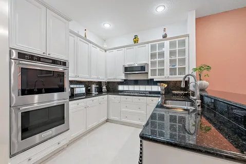 a kitchen with granite countertop white cabinets white appliances and sink