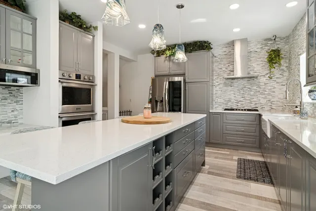 a kitchen with stainless steel appliances kitchen island granite countertop a sink stove and refrigerator