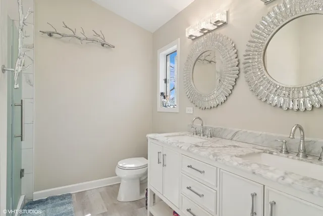 a bathroom with a granite countertop toilet a sink and a mirror