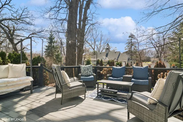 a view of a patio with couches and a fire pit and wooden fence