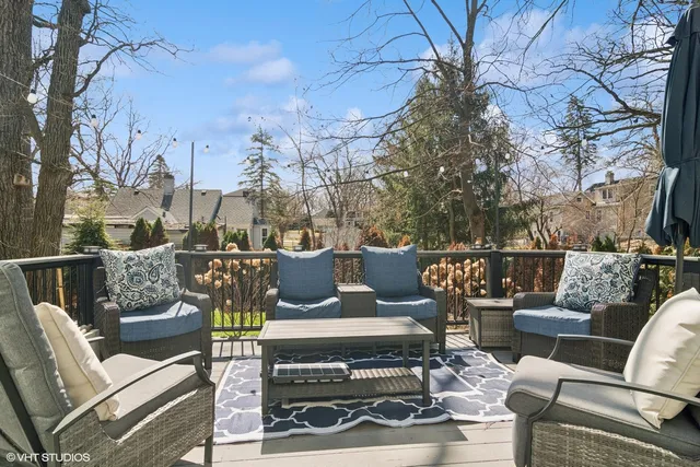a view of a patio with couches chairs and a fire pit with large trees