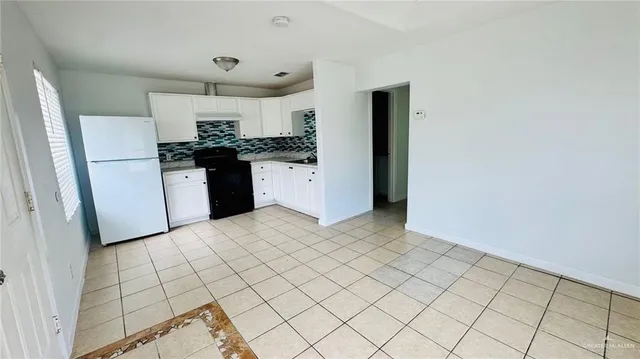 a kitchen with a refrigerator and white cabinets