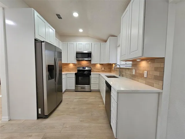 a kitchen with kitchen island granite countertop a stove a sink and a refrigerator with wooden floor