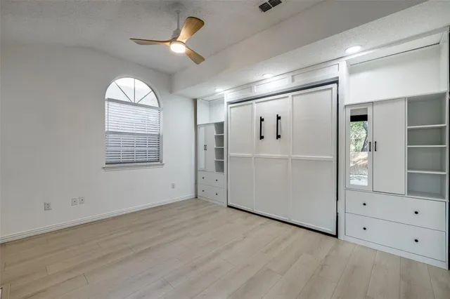 an empty room with wooden floor mirror and windows