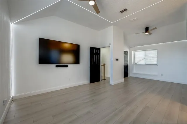an empty room with wooden floor cabinet and windows