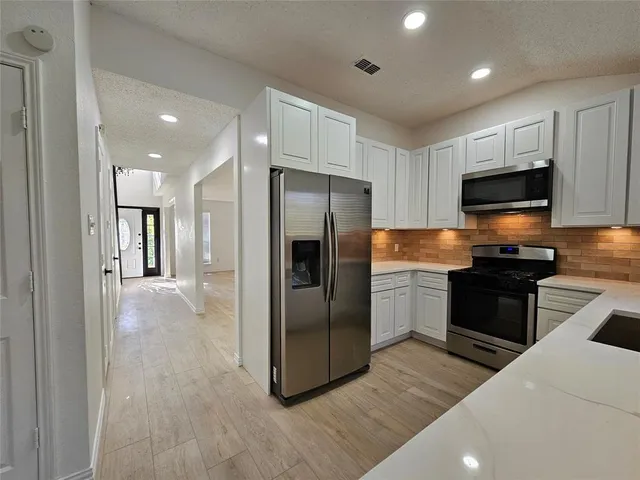 a kitchen with a refrigerator and a stove top oven