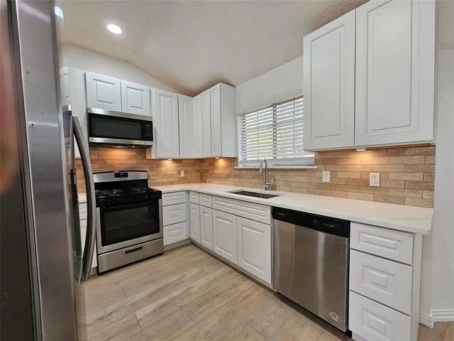 a kitchen with granite countertop a refrigerator sink and microwave