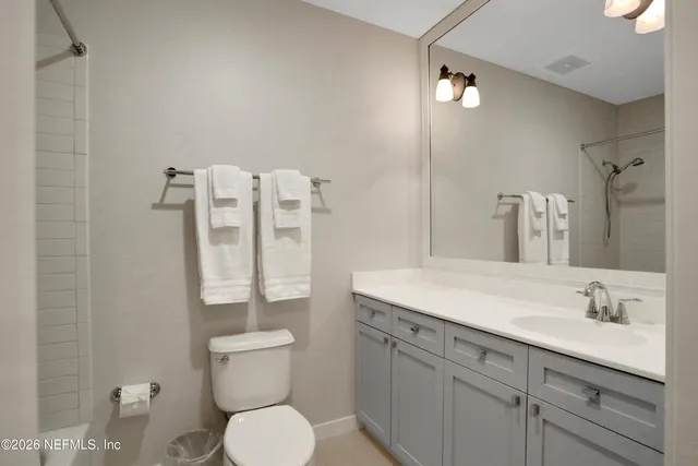 a bathroom with a granite countertop toilet sink and mirror
