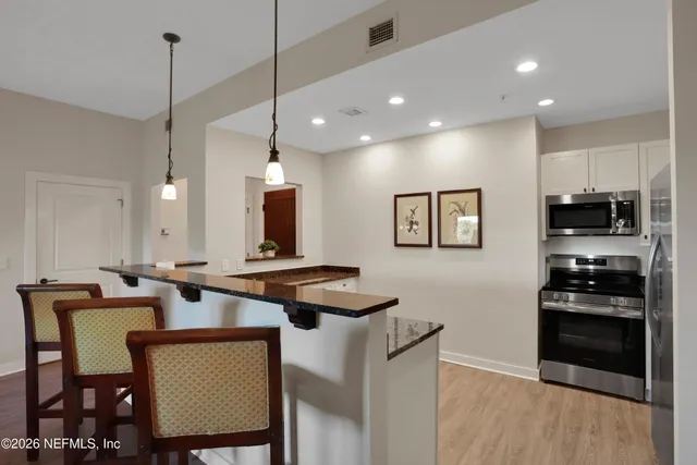 a kitchen with stainless steel appliances granite countertop a stove a sink a microwave a dining table and chairs