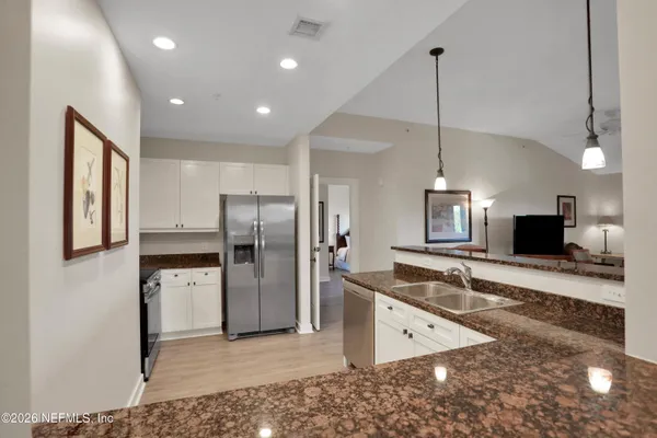 a kitchen with stainless steel appliances granite countertop a refrigerator a sink and a stove