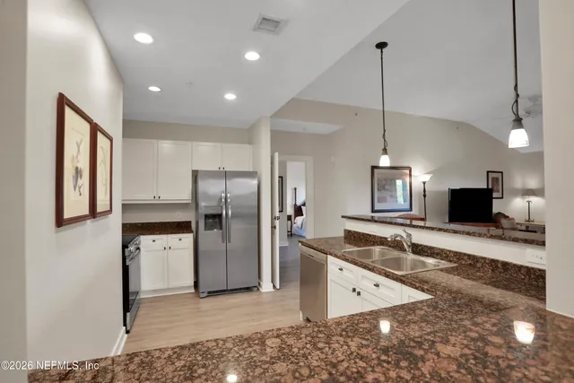 a kitchen with stainless steel appliances granite countertop a refrigerator a sink and a stove