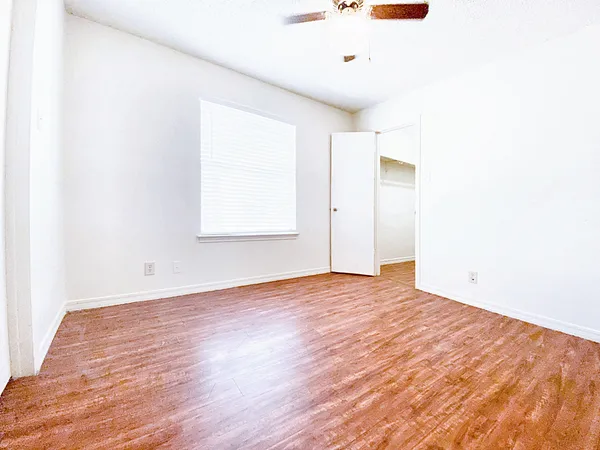 a view of an empty room with wooden floor and a window