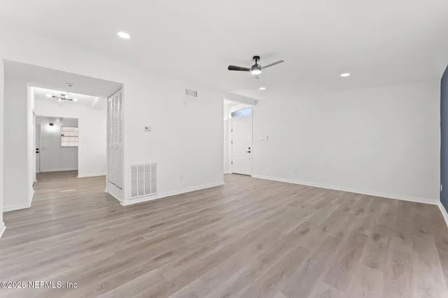 a view of an empty room with a window and wooden floor