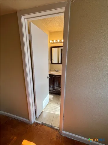 a view of a hallway with wooden floor and a kitchen