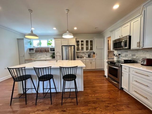 a kitchen with stainless steel appliances kitchen island granite countertop a kitchen island hardwood floor and a sink