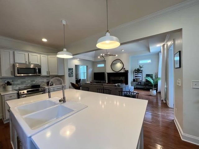 a large kitchen with kitchen island a large island in the center a sink a stove and a wooden floors