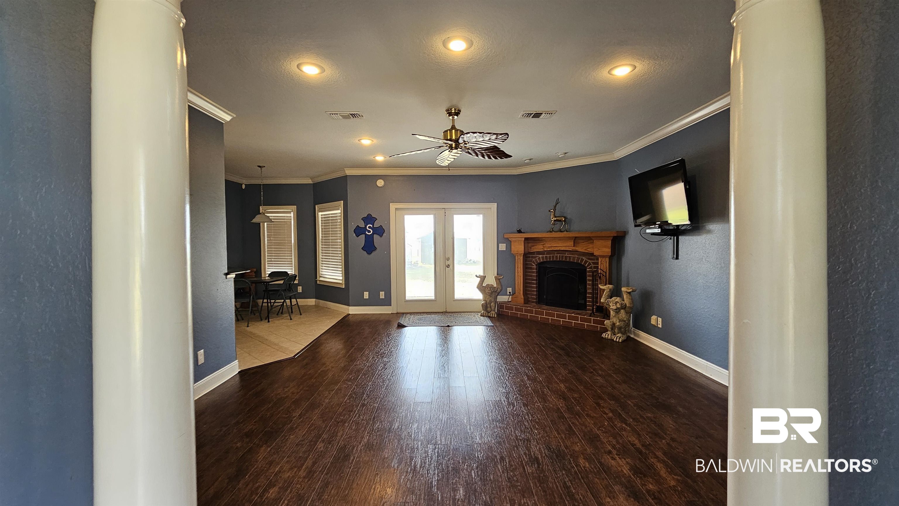 9275 Crawford Road Elberta, AL 36530 - Photo 19 of 28 Unfurnished living room featuring a textured wall, wood finished floors, a fireplace, ceiling fan, and crown molding