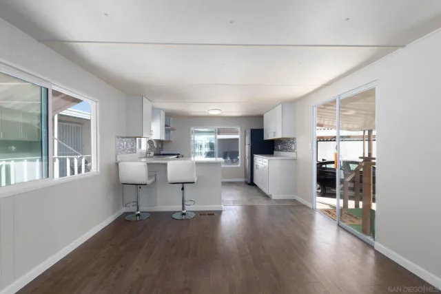 a living room with furniture wooden floor and a kitchen
