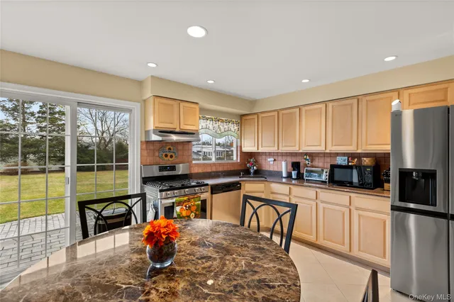 a kitchen with stainless steel appliances kitchen island granite countertop a stove top oven a sink a dining table and chairs