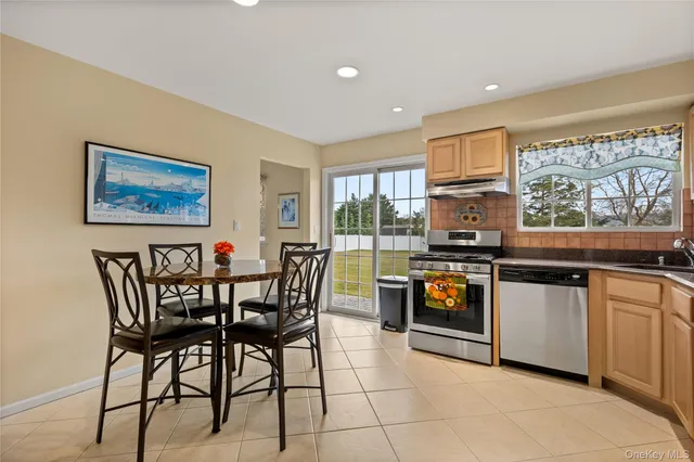 a kitchen with stainless steel appliances granite countertop a stove a sink a dining table and chairs