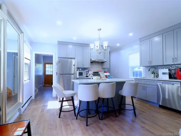 a kitchen with stainless steel appliances a dining table chairs and wooden floor