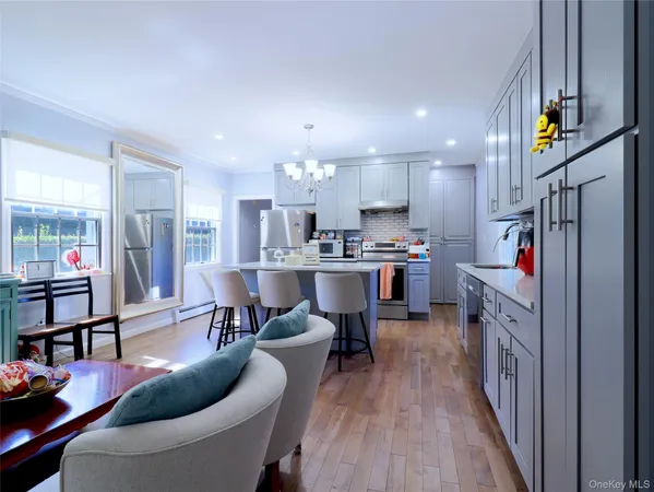 a living room with stainless steel appliances furniture a rug kitchen view and a faucet