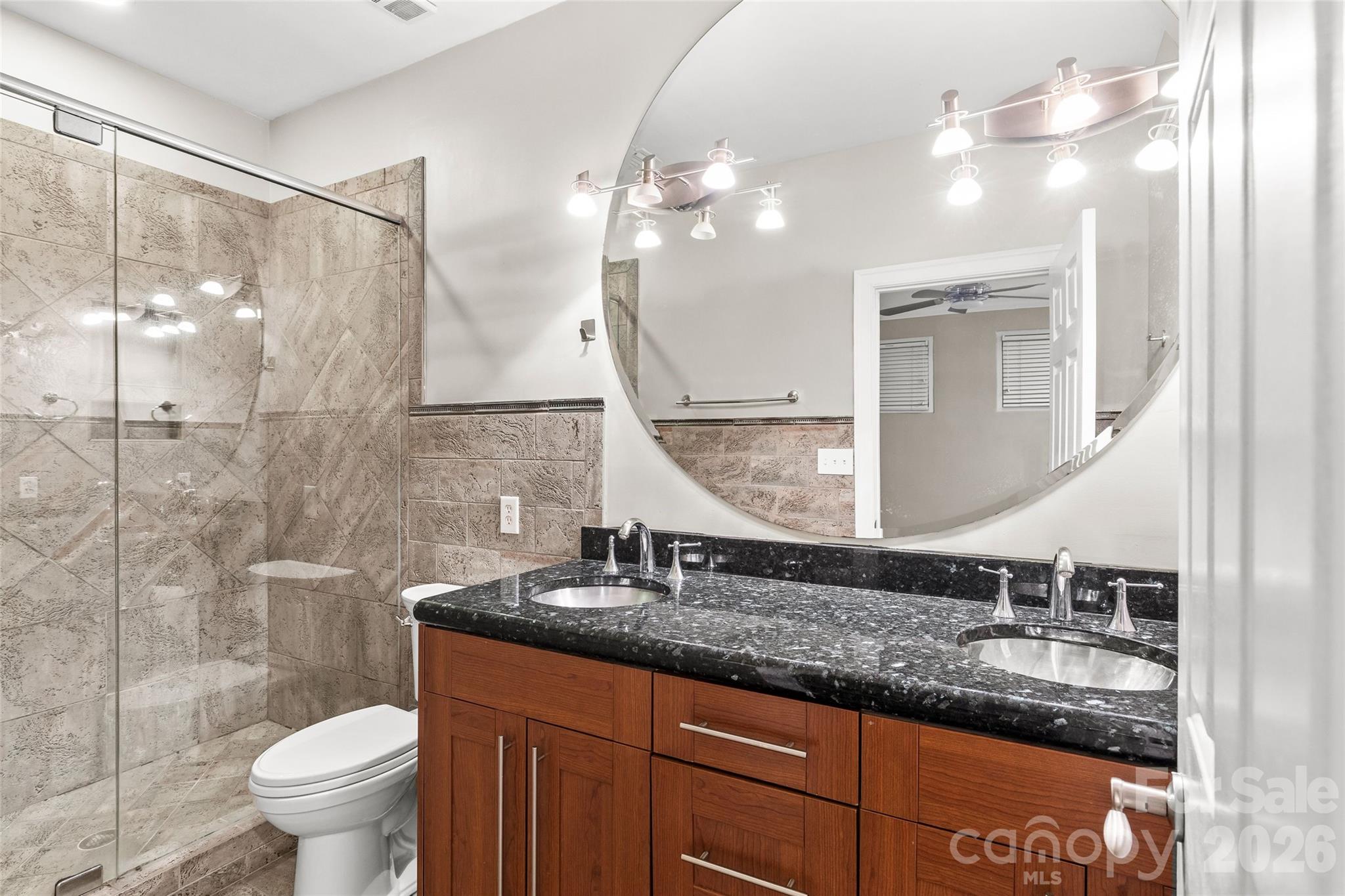 127 North Tryon Street, Unit 410 Charlotte, NC 28246 - Photo 13 of 37 a bathroom with a granite countertop sink a toilet and a mirror