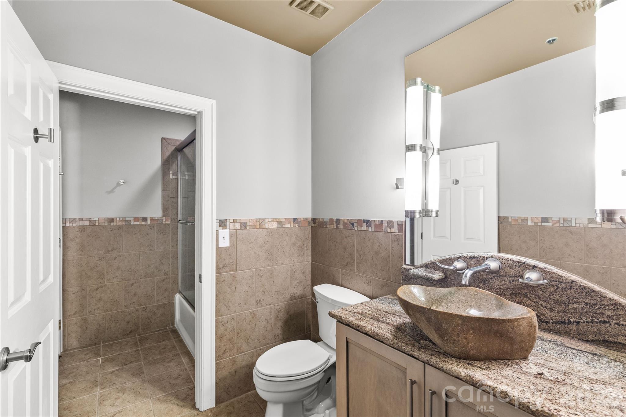 127 North Tryon Street, Unit 410 Charlotte, NC 28246 - Photo 14 of 37 a bathroom with a granite countertop sink a toilet and shower