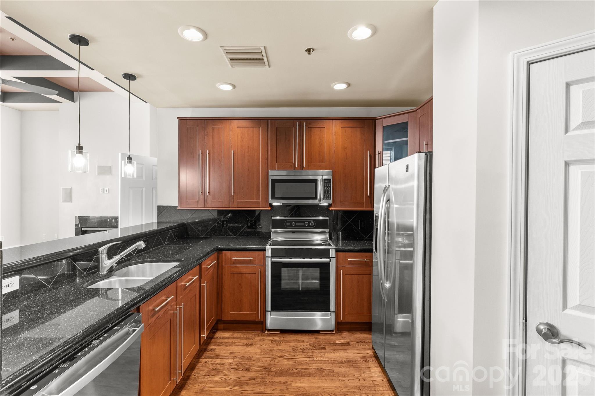 127 North Tryon Street, Unit 410 Charlotte, NC 28246 - Photo 16 of 37 a kitchen with stainless steel appliances granite countertop a refrigerator and a sink