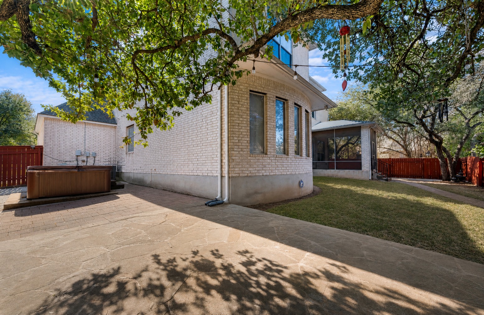 3903 Remington Road Cedar Park, TX 78613 - Photo 29 of 29 Mature trees shade a brick exterior with a screened porch and a paved patio featuring an outdoor spa.