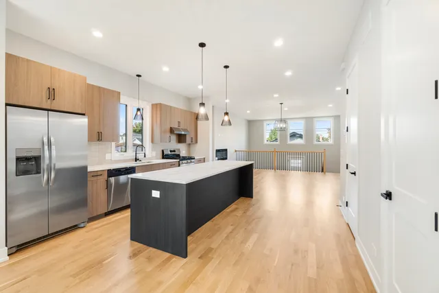 a large kitchen with stainless steel appliances kitchen island granite countertop a large counter top and wooden floors