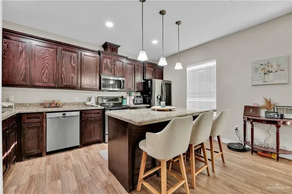 a kitchen with granite countertop a stove a sink a dining table and chairs with wooden floor