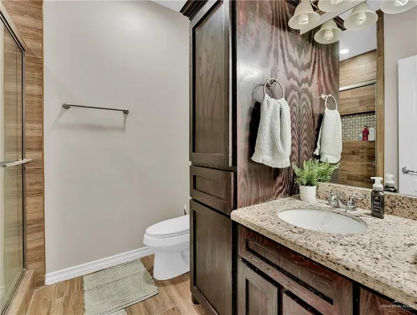a bathroom with a granite countertop sink toilet and a mirror