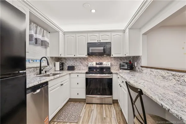 a kitchen with stainless steel appliances granite countertop a sink stove and cabinets