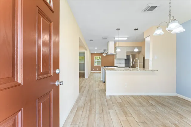 a view of a kitchen with kitchen island wooden floor center island and stainless steel appliances