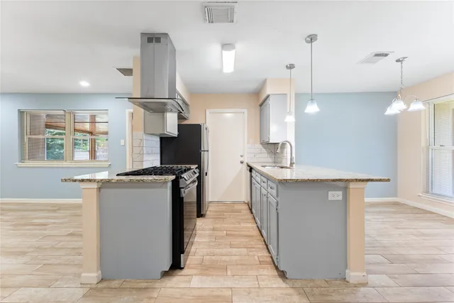 a kitchen with stainless steel appliances granite countertop a sink a stove and a wooden floor