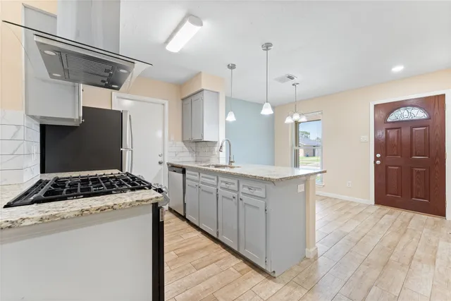 a kitchen with a stove a sink a refrigerator and wooden floor