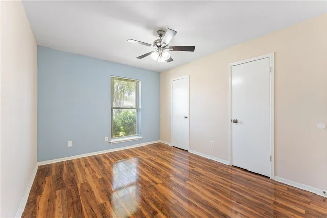a view of an empty room with window and wooden floor