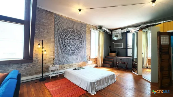 a spacious bedroom with a bed and wooden floor