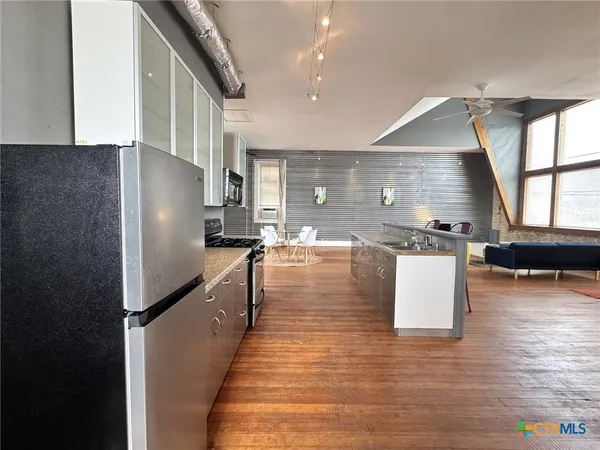 a kitchen with stainless steel appliances granite countertop a refrigerator a stove and a wooden floors