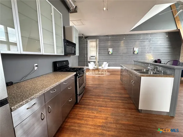 a kitchen with stainless steel appliances granite countertop a stove a sink and a microwave
