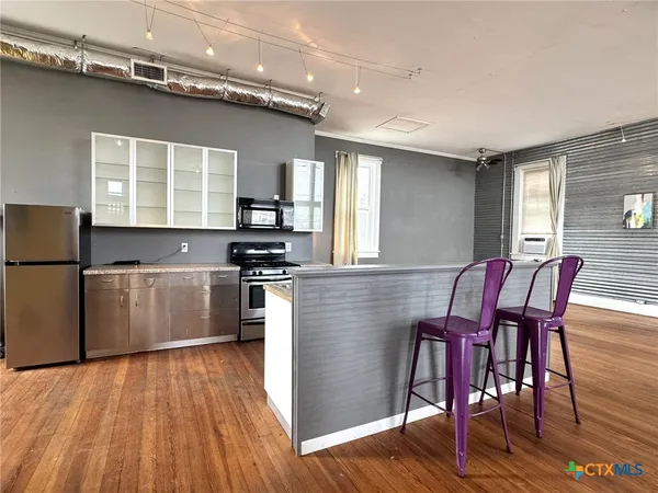 a kitchen with granite countertop a stove top oven a sink dishwasher a dining table and chairs with wooden floor