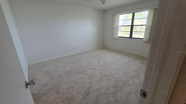 an empty room with chandelier fan and windows