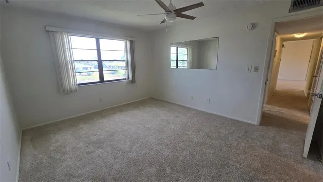 an empty room with a window and a ceiling fan